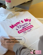 Heat press machine with a white garment and pink text design on it from Cows Corner