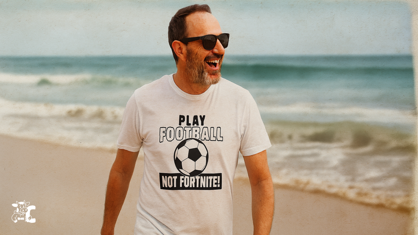 Man wearing a t-shirt with 'Play Football Not Fortnite' on a beach showcasing Cows Corner product