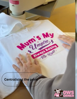 White hoodie with printed text 'Mum's My Umpire Always Raising Me Right' being centralised on a heat press machine from Cows Corner