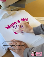 Person removing a printed film from a white shirt with text on it from Cows Corner
