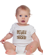 A baby wearing a baby grow with Dads Like a Spin Bowler, Always Full of Tricks, on the front! Funny Cricket Baby Bodysuit, Organic or In-Conversion to Organic Cotton, Self Fabric Bound Neckline, Cuffs and Leg Openings
