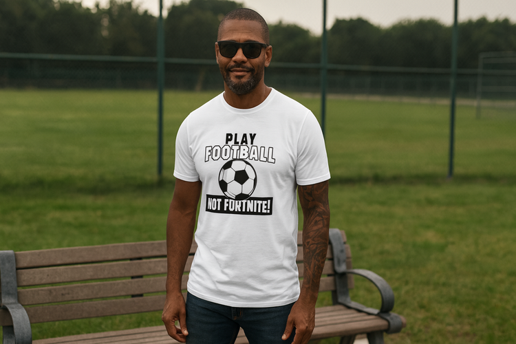 Man wearing a white t-shirt with a sports-themed design on a grassy field.