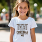 A girl wearing a white t-shirt with the funny football slogan on the front saying 'Dad’s First Love: Football. Dad’s Second Love: Me'