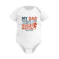 White baby onesie with colorful text on a white background with the Cows Corner slogan saying My dad tackles life like a rugby match - head first.