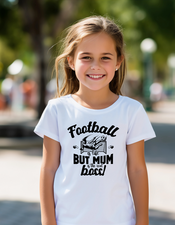 Young girl wearing a white t-shirt with text in an outdoor setting with the slogan Football is life, but mum is the real boss! 
