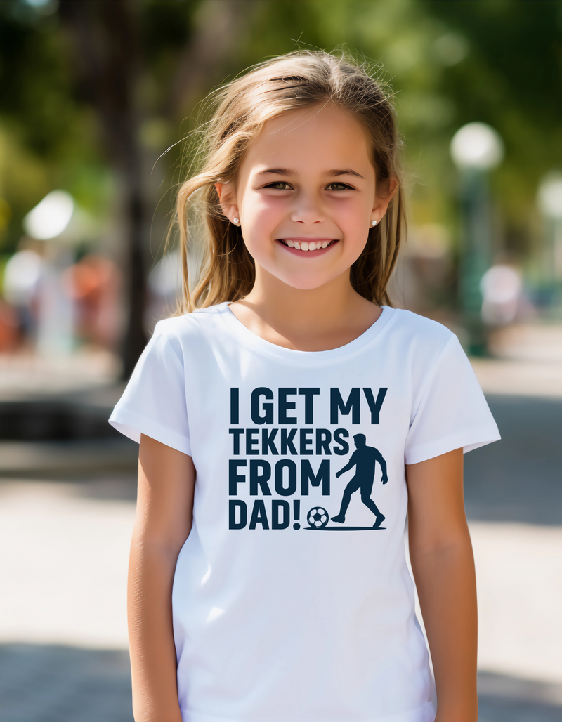 A young girl wearing a t-shirt with the funny football slogan on the front saying 'I Get My Tekkers From Dad'