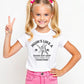 A little girl wearing a white t-shirt with Mums Like A Good Bat Grip, Always Holding Things Together on the front. A Funny Cricket T-Shirt, Premium Fabric, Multiple Junior Sizes, Perfect for Boys and Girls