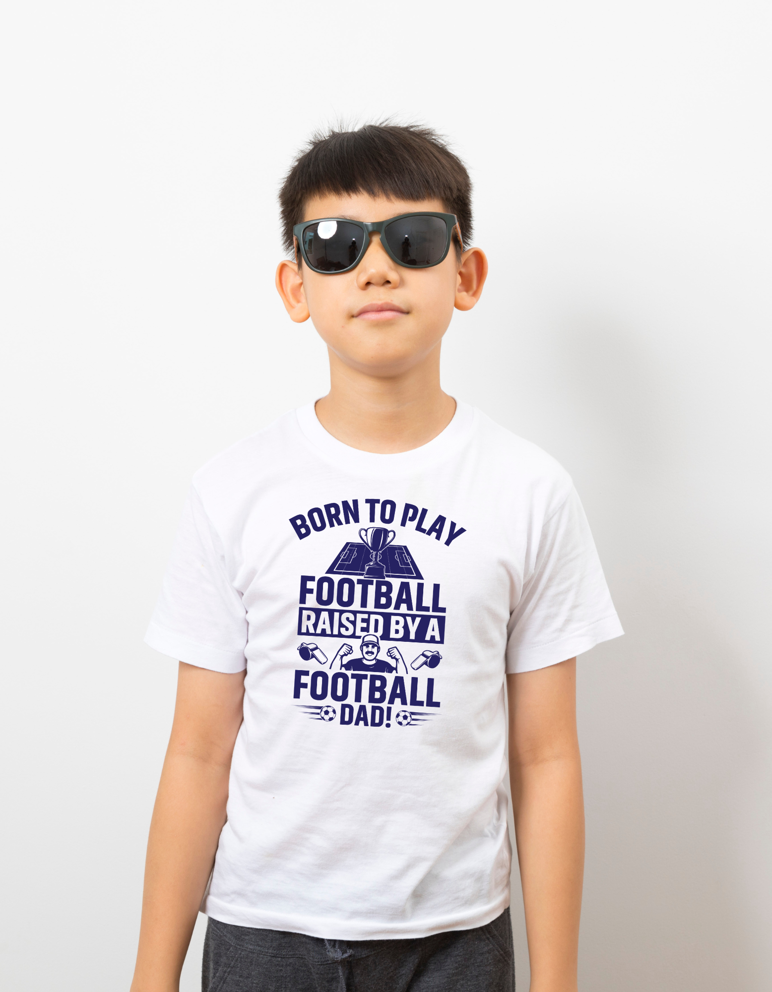 A boy wearing a white t-shirt with the funny football saying that says I love my dad 'Born To Play Football. Raised by a Football Dad!'