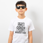 A boy wearing a white t-shirt with the funny football slogan on the front saying 'Messi, Ronaldo…Nah ’My Dads the Real Goat!