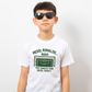 A little boy wearing a white t-shirt with the funny football and dad loving slogan on the front which reads 'Messi, Ronaldo…Nah ’My Dads the Real Goat!'