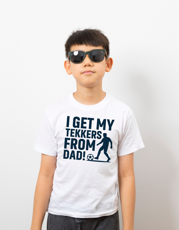 A young boy wearing a t-shirt with the funny football slogan on the front saying 'I Get My Tekkers From Dad'
