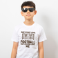 A boy wearing a white t-shirt with the funny football slogan on the front saying 'Dad’s First Love: Football. Dad’s Second Love: Me'