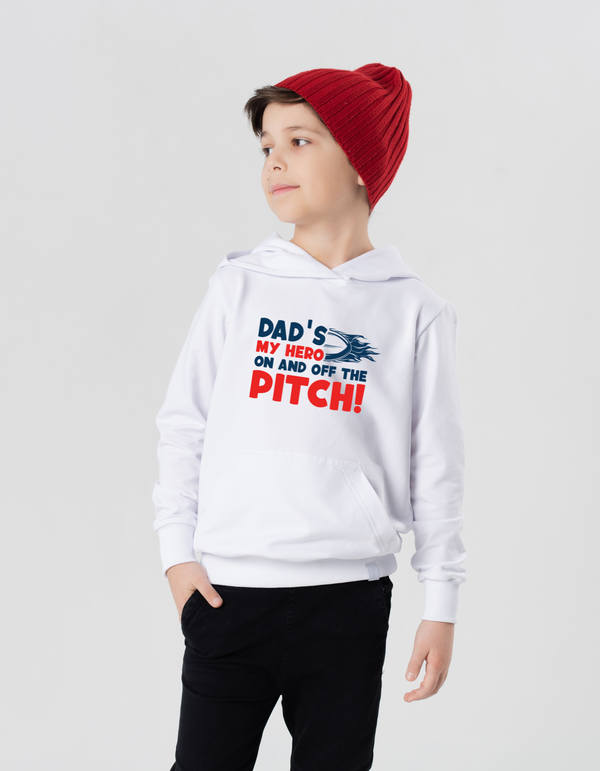 Child wearing a white hoodie with text, standing against a plain background with the Cows Corner slogan saying Dad's my hero on and off the pitch