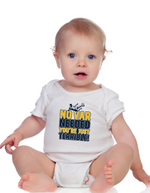 A a little baby wearing a white baby grow with the funny football slogan on the front saying 'No VAR Needed You’re Just Terrible'