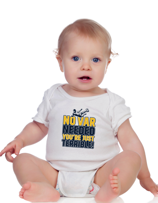A a little baby wearing a white baby grow with the funny football slogan on the front saying 'No VAR Needed You’re Just Terrible'