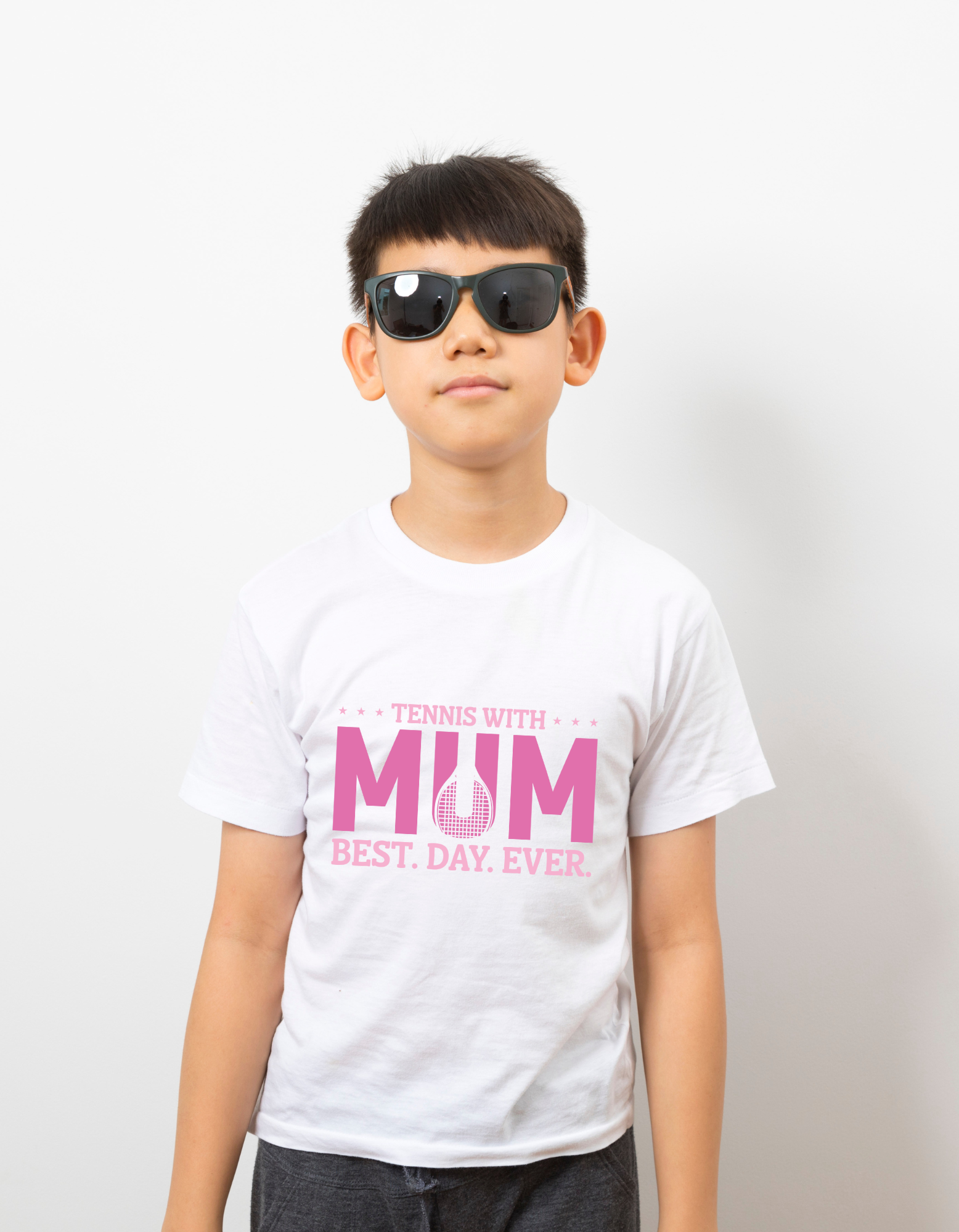 A boy wearing a white t-shirt with the lovely tennis saying on the front that reads 'Tennis with Mums. Best. Day. Ever!'