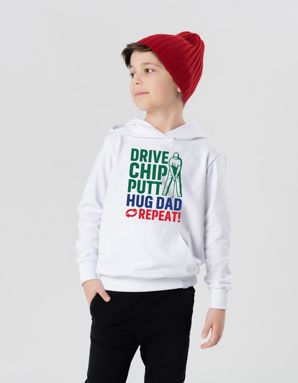 Child wearing a white hoodie with text and a graphic, standing against a plain background with a Cows Corner slogan saying Drive, Chip, Putt, Hug Dad, Repeat.