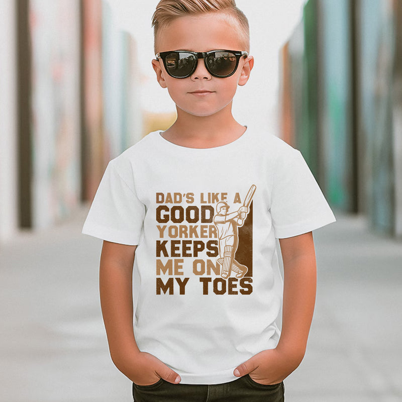 A little girl wearing a white t-shirt with Dads Like A Good Yorker, Keeps Me On My Toes on the front. A Funny Cricket T-Shirt, Premium Fabric, Multiple Junior Sizes, Perfect for Boys and Girls