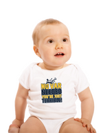 A a little baby wearing a white baby grow with the funny football slogan on the front saying 'No VAR Needed You’re Just Terrible'