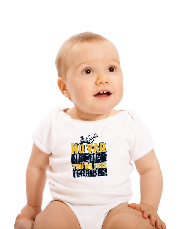 A a little baby wearing a white baby grow with the funny football slogan on the front saying 'No VAR Needed You’re Just Terrible'