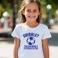 A little girl wearing a white t-shirt with a funny football slogan on the front that reads 'Dribble You Can Barely Walk Straight!'