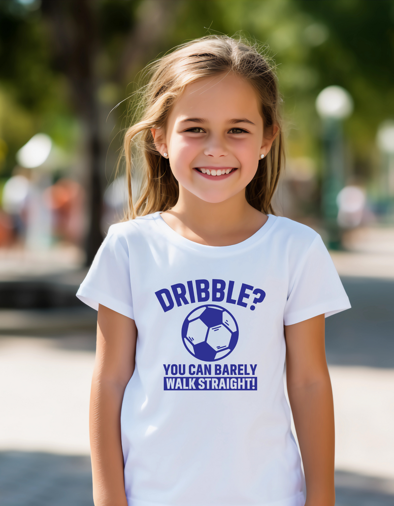 A little girl wearing a white t-shirt with a funny football slogan on the front that reads 'Dribble You Can Barely Walk Straight!'