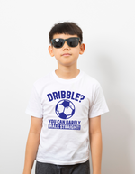A little baby wearing a white t-shirt with a funny football slogan on the front that reads 'Dribble You Can Barely Walk Straight!'