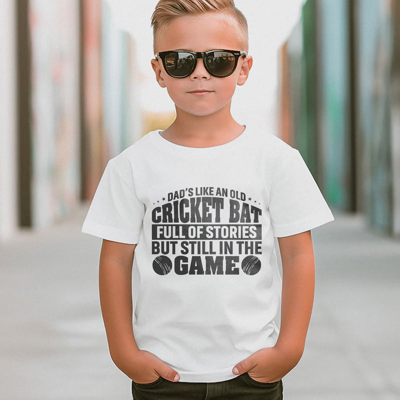 A little boy wearing a white t-shirt with Dads Like An Old Cricket Bat, Full Of Stories But Still In The Game on the front! A Funny Cricket Tee, Premium Fabric, Multiple Junior Sizes, Perfect for Boys and Girls
