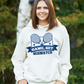 A lady wearing a white hoodie that has a funny tennis slogan on the front that reads 'Game, Set, Mismatch'