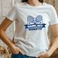A lady wearing a white t-shirt that has a funny tennis slogan on the front that reads 'Game, Set, Mismatch'