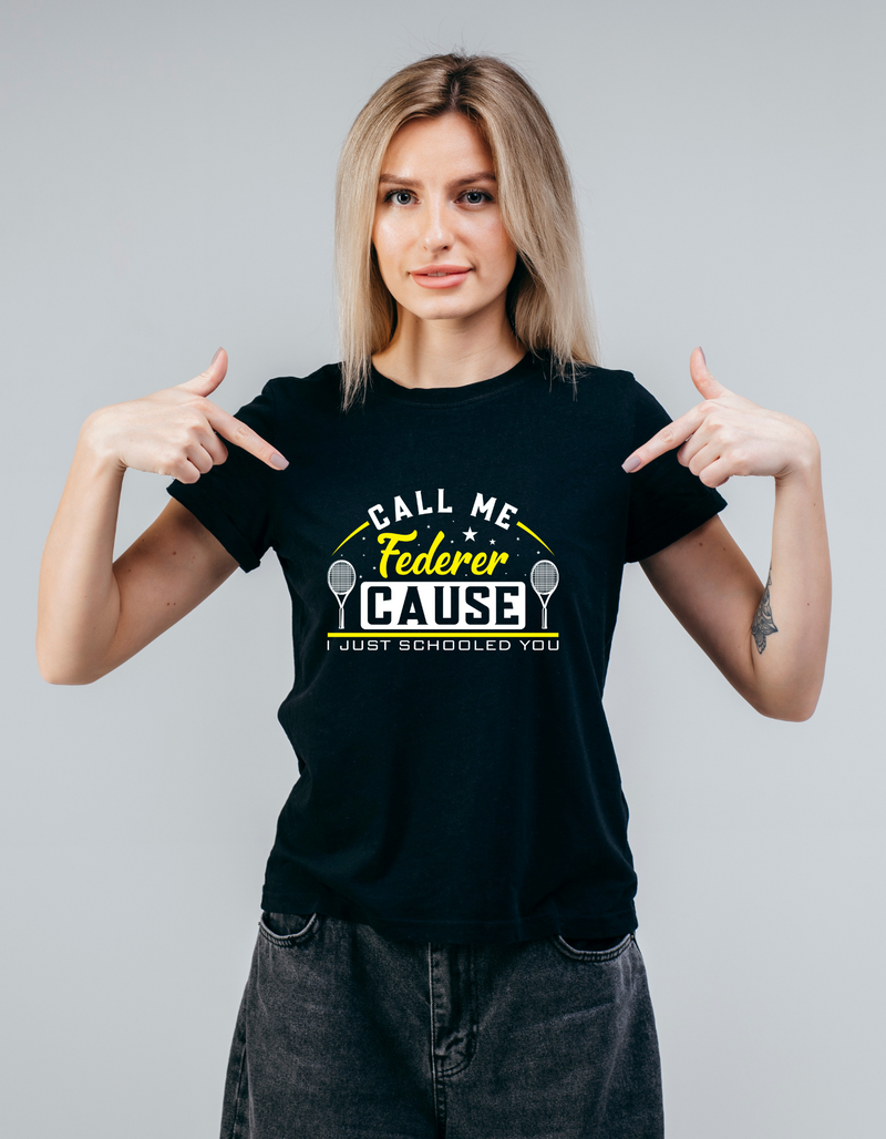 A lady wearing a black t-shirt with the funny tennis slogan on the front that reads 'Call Me Federer ’Cause I Just Schooled You'