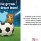 Newborn baby announcement card with soccer ball, teddy bear, and baby onesie on a grassy field background. A Cows Corner personalised card