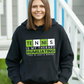 A lady wearing a black hoodie with the funny tennis slogan on the front that reads 'Tennis Is My Therapy, Humiliating You Is Just A Bonus'
