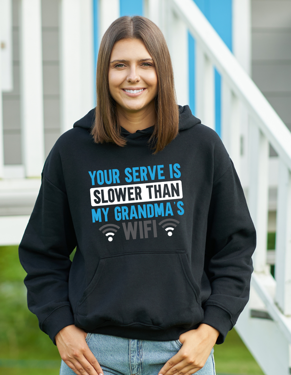 A lady wearing a black hoodie with the funny tennis slogan on the front which reads 'Your Serve Is Slower Than My Grandma's Wifi'