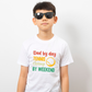 A boy wearing a white t-shirt with a funny tennis slogan on the front that reads 'Dad By Day, Tennis Champ By Weekend'