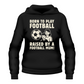Black hoodie with the text 'Born to Play Football Raised by a Football Mum!' printed on the front, along with an image of a soccer ball and a cartoon depiction of a child and a parent Cows Corner T-shirt