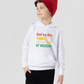 A little boy wearing a white hoodie with the funny tennis slogan on the front that reads 'Dad By Day, Tennis Champ By Weekend'