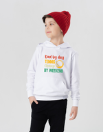A little boy wearing a white hoodie with the funny tennis slogan on the front that reads 'Dad By Day, Tennis Champ By Weekend'