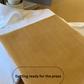 Text 'Getting ready for the press' on a yellow surface with a white cloth over the Cows Corner garment