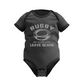 Black baby onesie with rugby design and text on a white background with a Cows Corner slogan saying Rugby where friendly matches leave scars.
