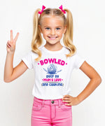A little girl wearing a white t-shirt with Bowled Over by My Mum’s Love & Cooking on the front. A Funny Kids Cricket T-Shirt, Multiple Junior Sizes, Perfect for Boys and Girls