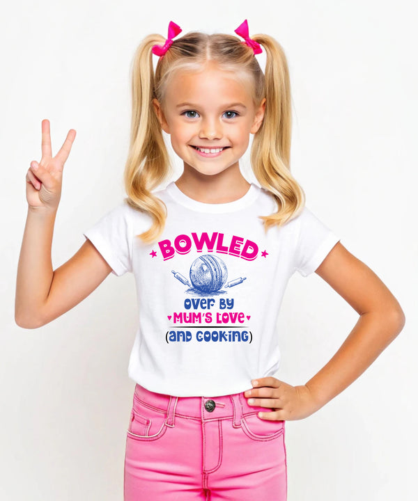 A little girl wearing a white t-shirt with Bowled Over by My Mum’s Love & Cooking on the front. A Funny Kids Cricket T-Shirt, Multiple Junior Sizes, Perfect for Boys and Girls