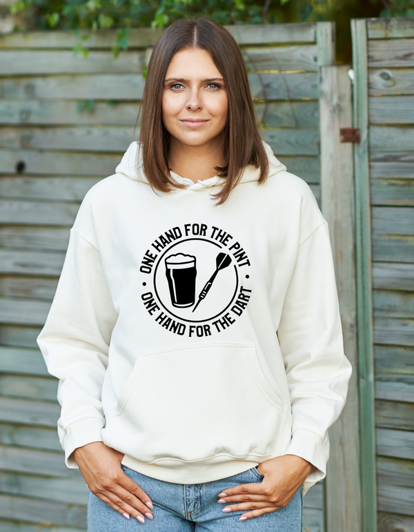 Person wearing a white hoodie with a graphic design outdoors with a Cows Corner slogan saying one hand for the pint one hand for the dart