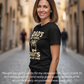 Woman wearing a black t-shirt with text on a street, featuring a product review. Cows Corner gifts are perfect for sport-mad fans, these gifts work brilliantly for birthdays, new baby celebrations, Father’s Day, Mother’s Day, Christmas, anniversaries, thank you gifts, end-of-season team awards, graduations, retirements, and just-because moments when you want to raise a smile. 
