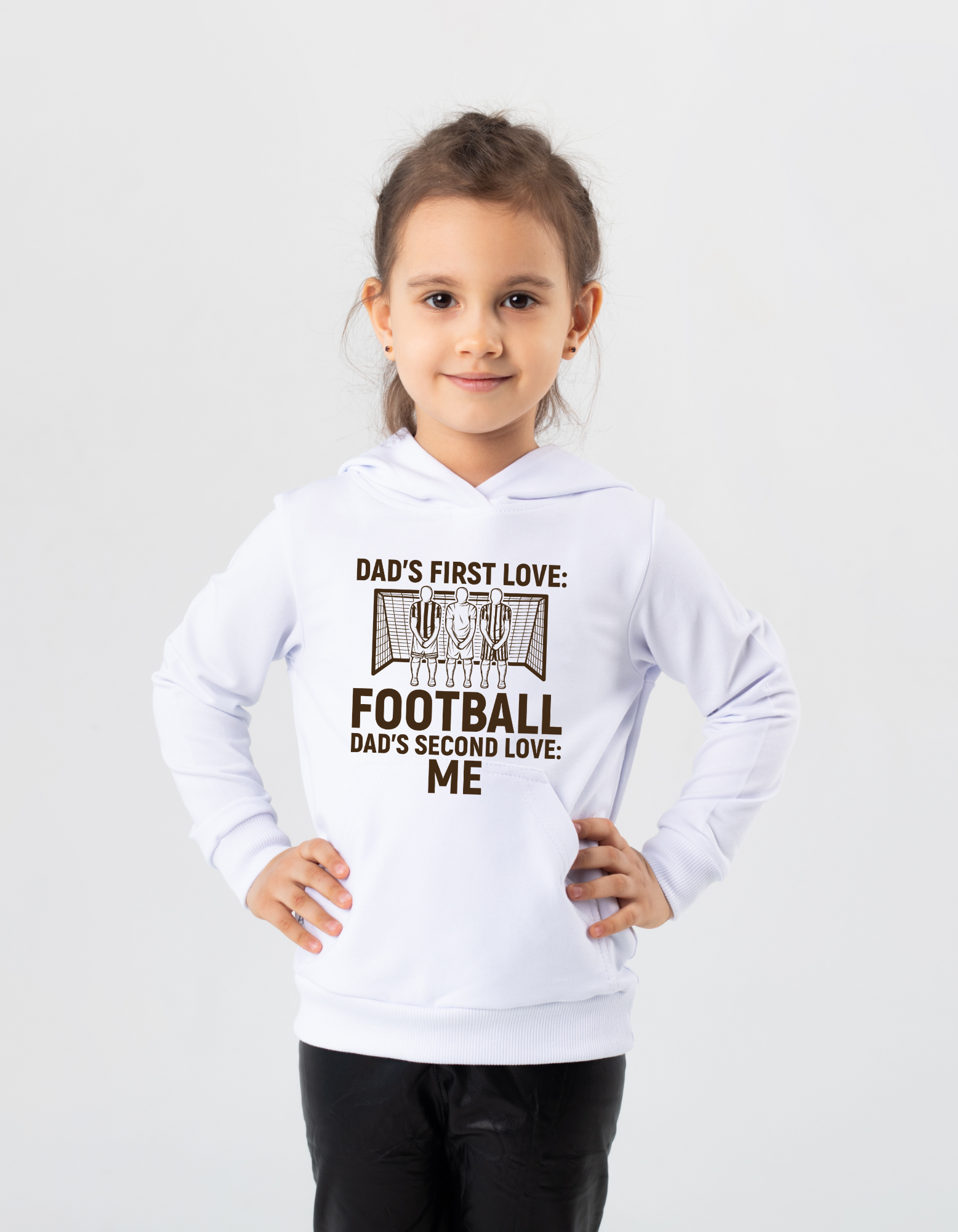 A young girl wearing a white hoodie with the funny football slogan on the front saying 'Dad’s First Love: Football. Dad’s Second Love: Me'