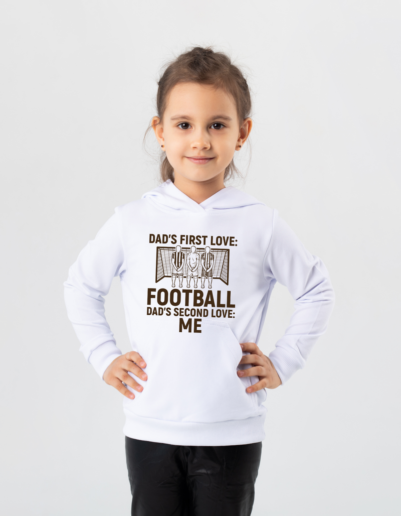 A young girl wearing a white hoodie with the funny football slogan on the front saying 'Dad’s First Love: Football. Dad’s Second Love: Me'