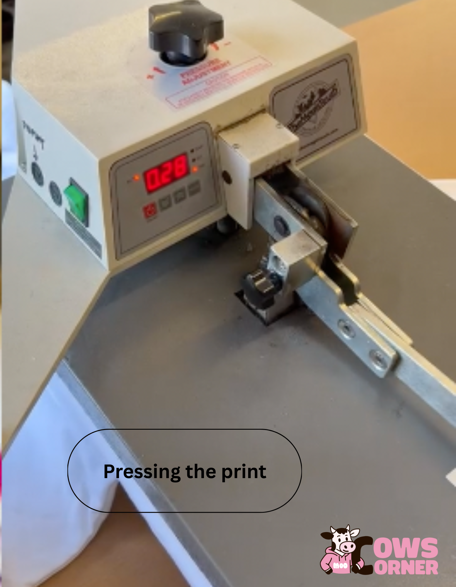 Printing process using a machine with a digital display, labeled 'Pressing the print' on a Cows Corner Hoodie