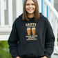 Woman wearing a black hoodie with a humorous darts and beer graphic with a Cows Corner slogan saying Darts the only sport where beeer improves performance.