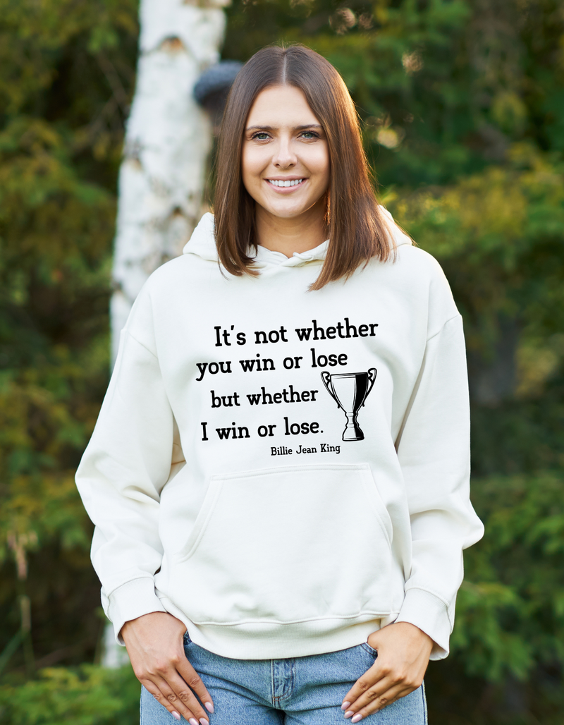 A lady wearing a white hoodie with the funny tennis slogan on the front reading 'It’s Not Whether You Win or Lose but Whether I Win or Lose – Billie Jean-King!