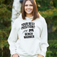 A lady wearing a white hoodie that has the funny football slogan on the front that reads 'Your Best Position? Bench Warmer'